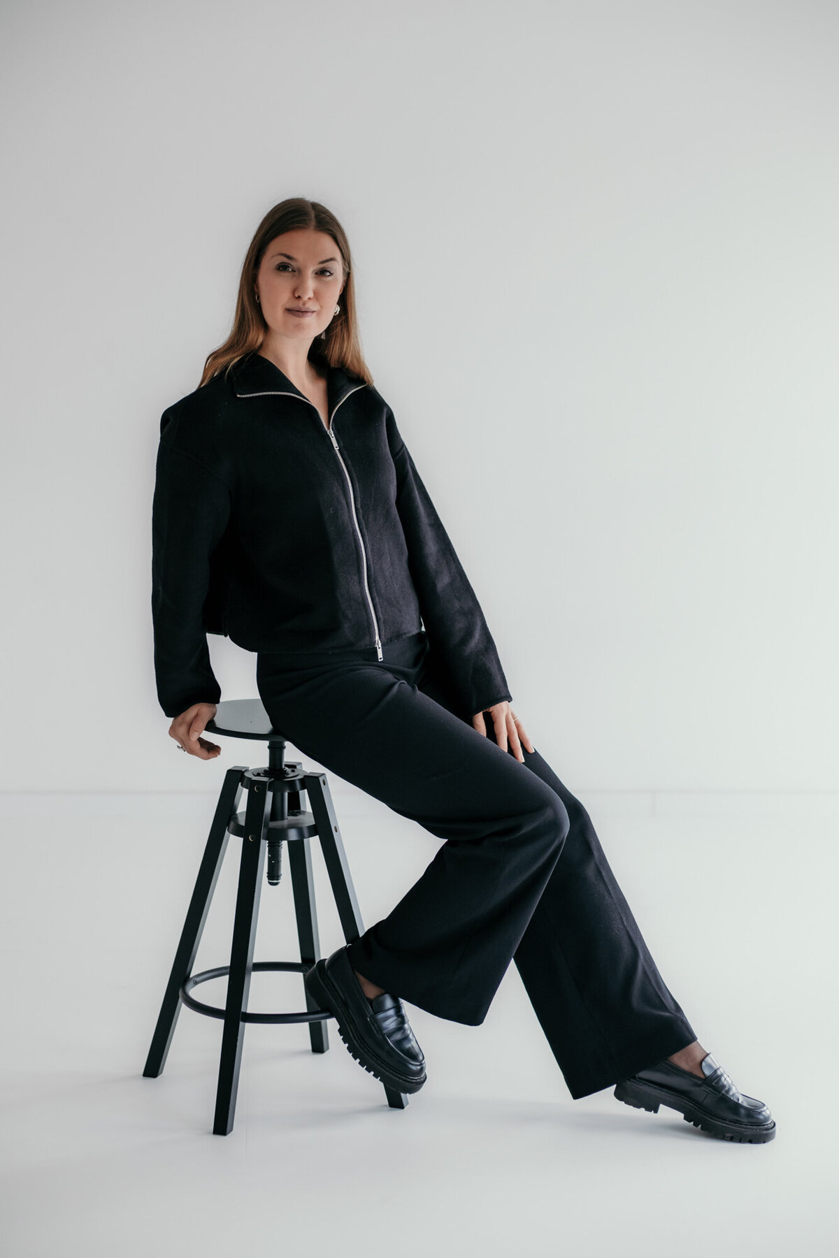 Woman sits confidently on a stool.