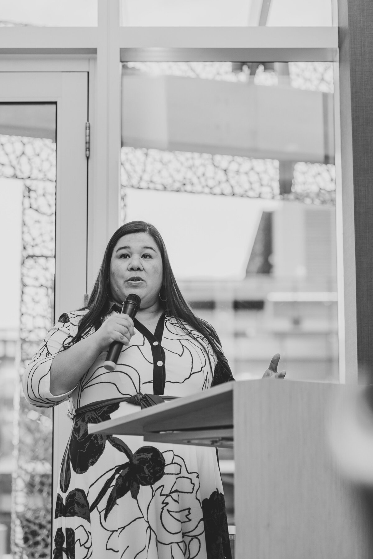 A speaker gives a talk at Equal pay Today in front of a glass window.