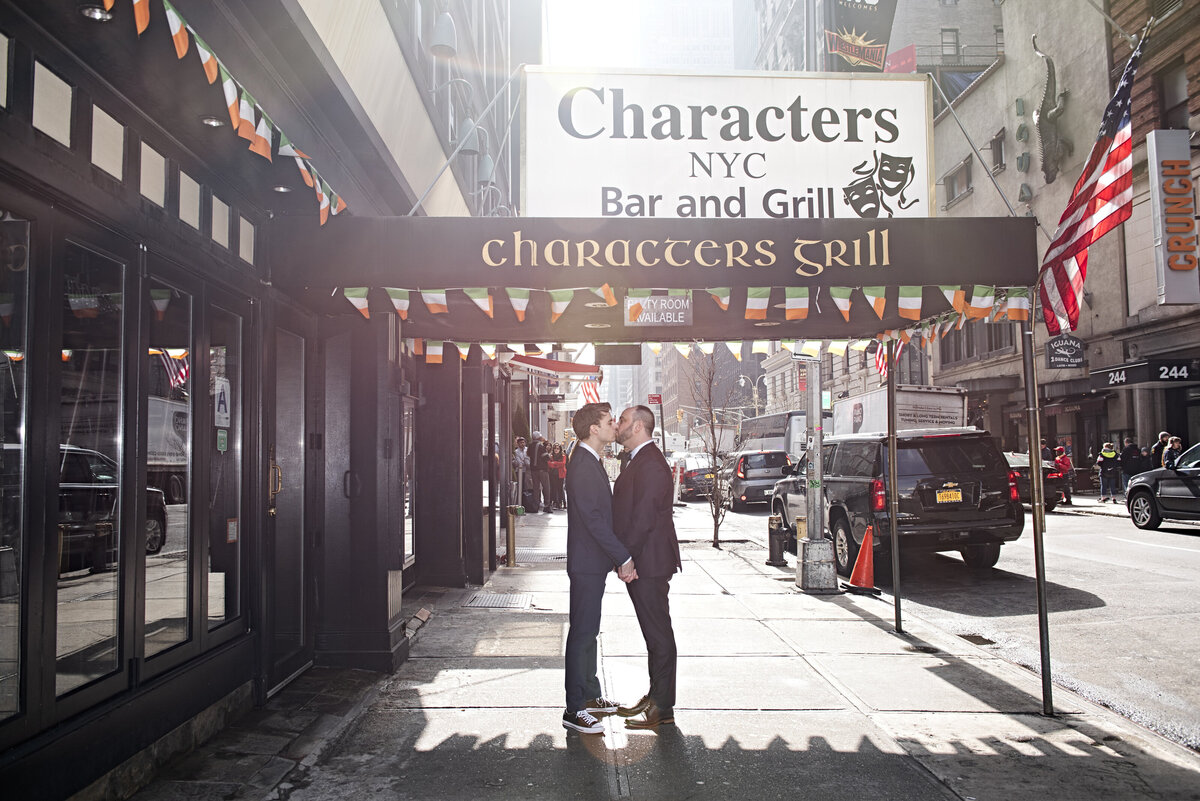 A couple kissing while standing outside a restaurant