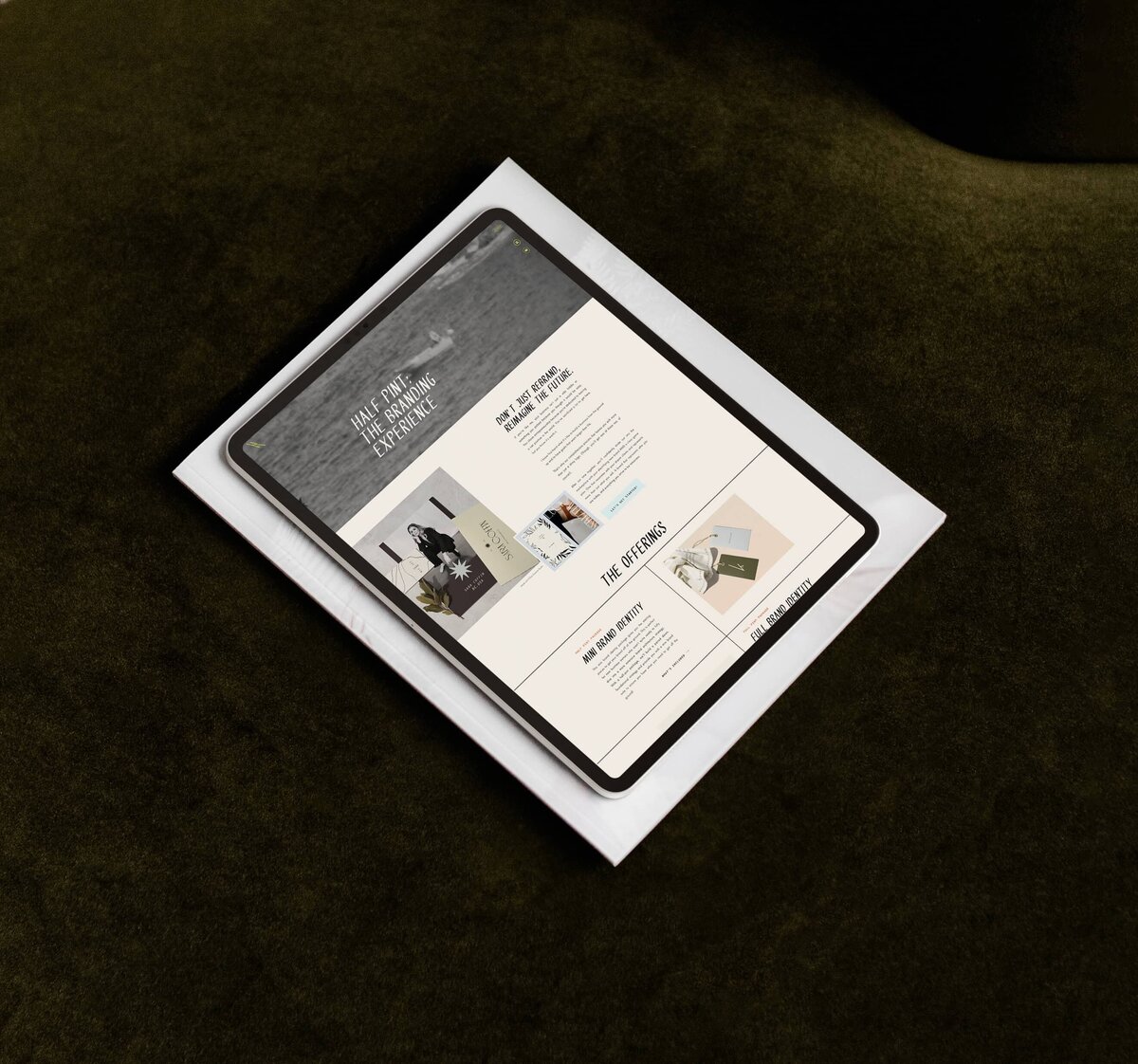 A tablet displaying a website sits atop a closed laptop, both positioned on a dark green surface—an inspiring setup for any branding designer.