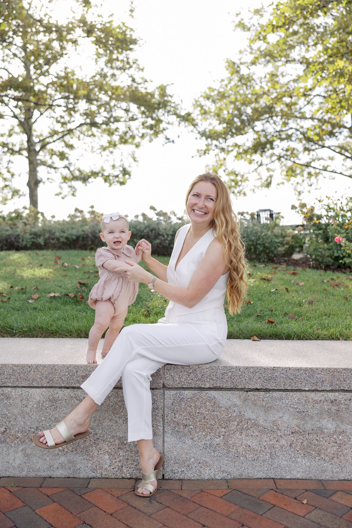 Mother poses with child in Boston wearing white pant suite.