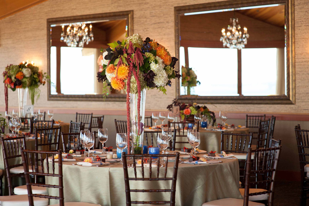elevated fall centerpieces on glass vase with orange roses, dahlias, hydrangea, amaranthus