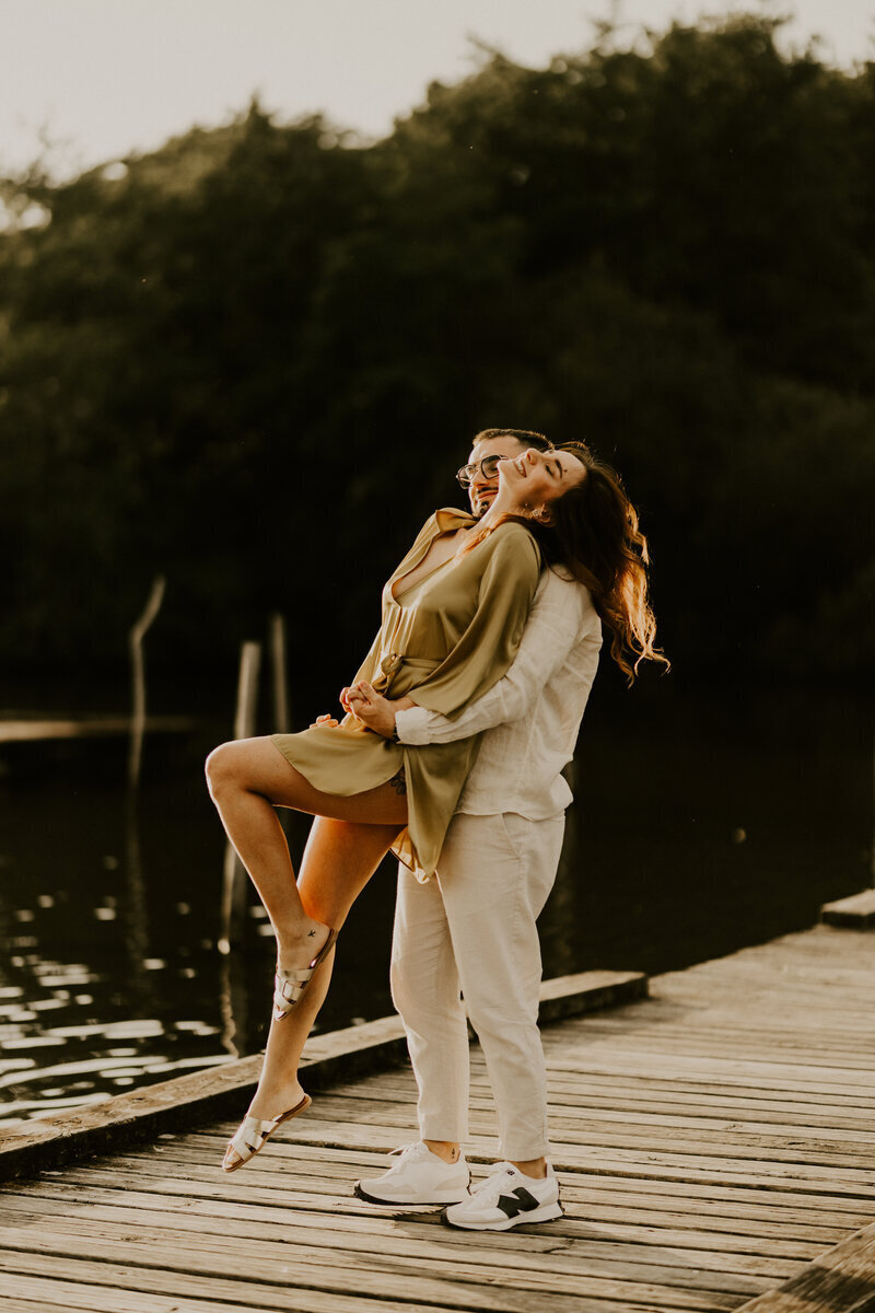 Homme faisant un porté avec sa femme sur un ponton en bois lors d'une séance photo couple en Vendée.