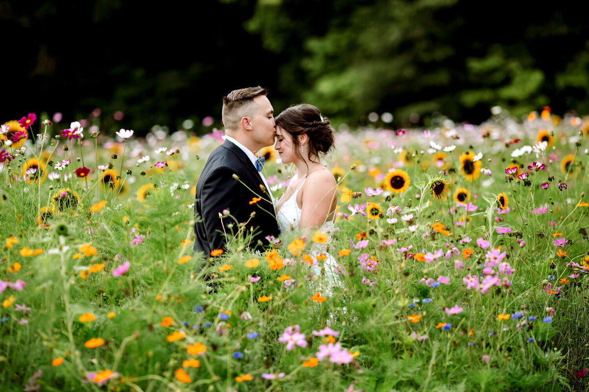 Bride and groom sharing a kiss in a vibrant wildflower field.