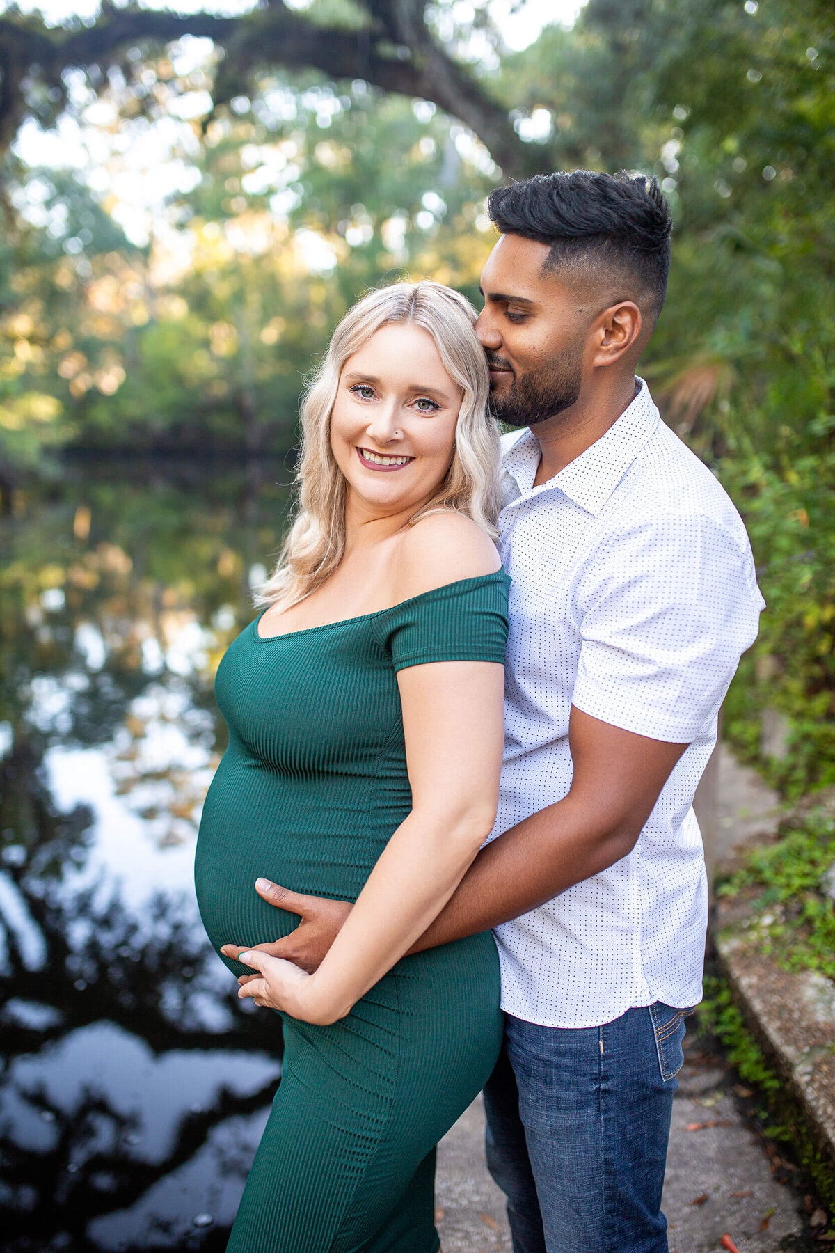 Tampa maternity photographer captures man holding wifes belly from behind while kissing her head at Hillsborough River State Park 