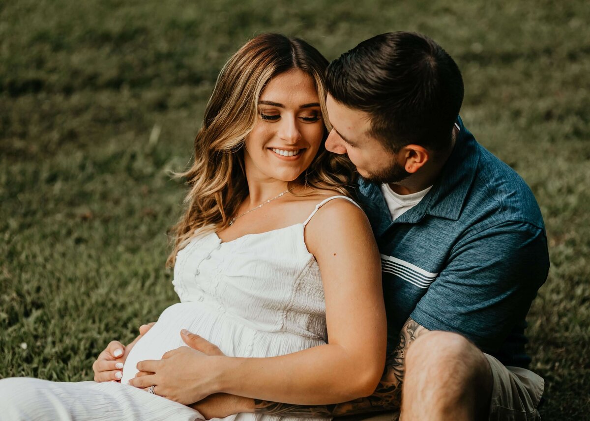 A pregnant couple embracing in the grass during their Pittsburgh maternity session.