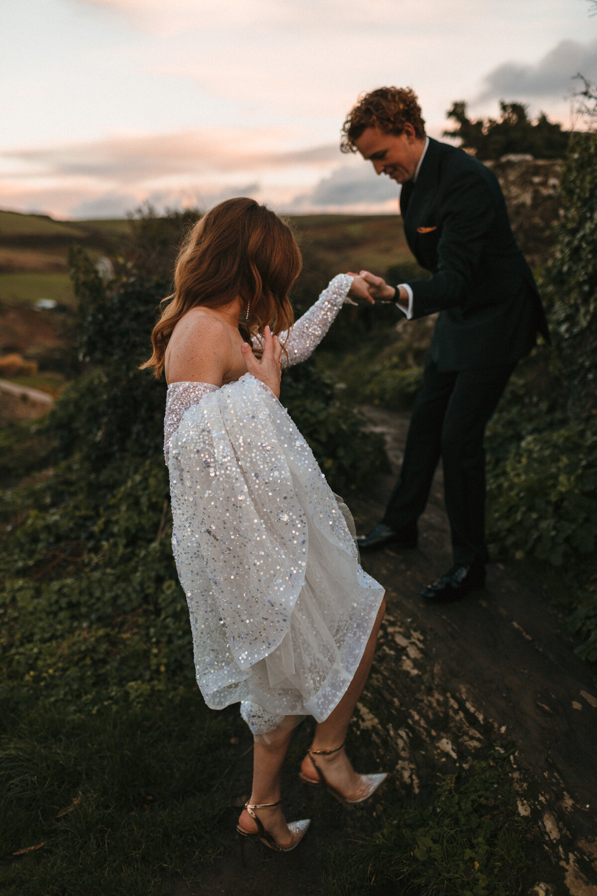 Groom helps his bride up rocks at Gara Rock hotel