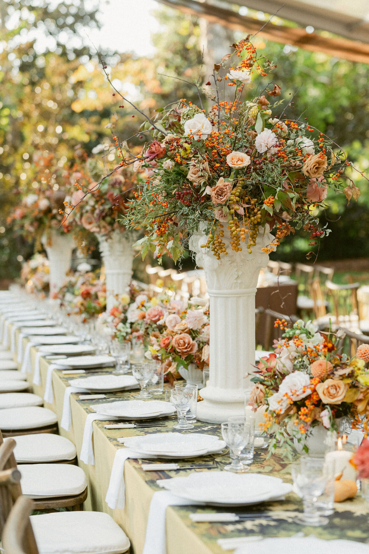 Lush fall florals for low and high centerpieces at fall wedding reception. Clear tented wedding reception in the family's back yard creating an intimate wedding reception environment. Whimsical and organic floral design in colors of copper, yellow, blush,and brown. Fall florals with sweet peas, dahlias, butterfly ranunculus, roses, mums, and bittersweet berries. Design by Rosemary & Finch Floral Design in Nashville, TN.