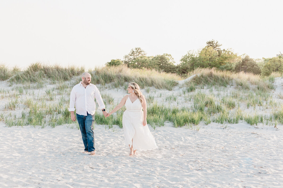 Couple strolls hand in hand on a beach during their engagement session