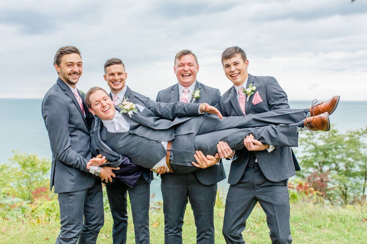 groomsmen hold up groom