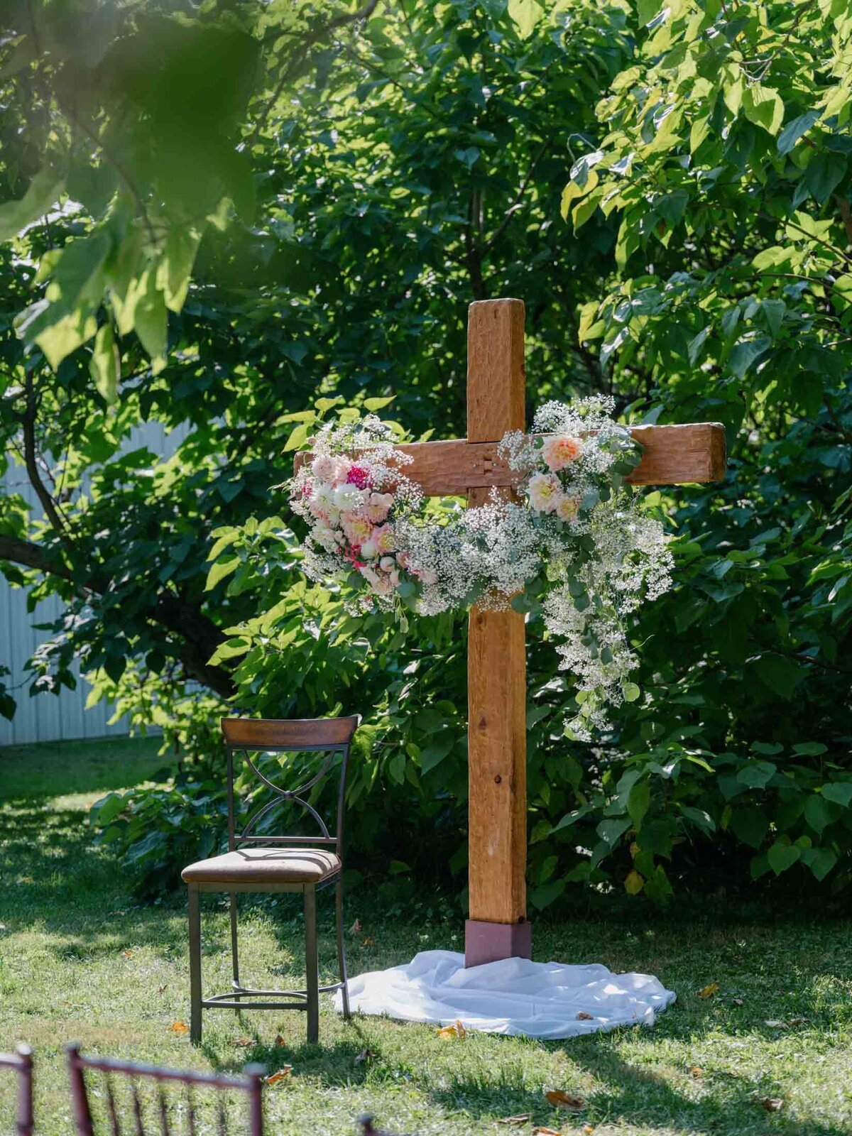 Cross decorated with florals for an outdoor wedding altar centerpiece.