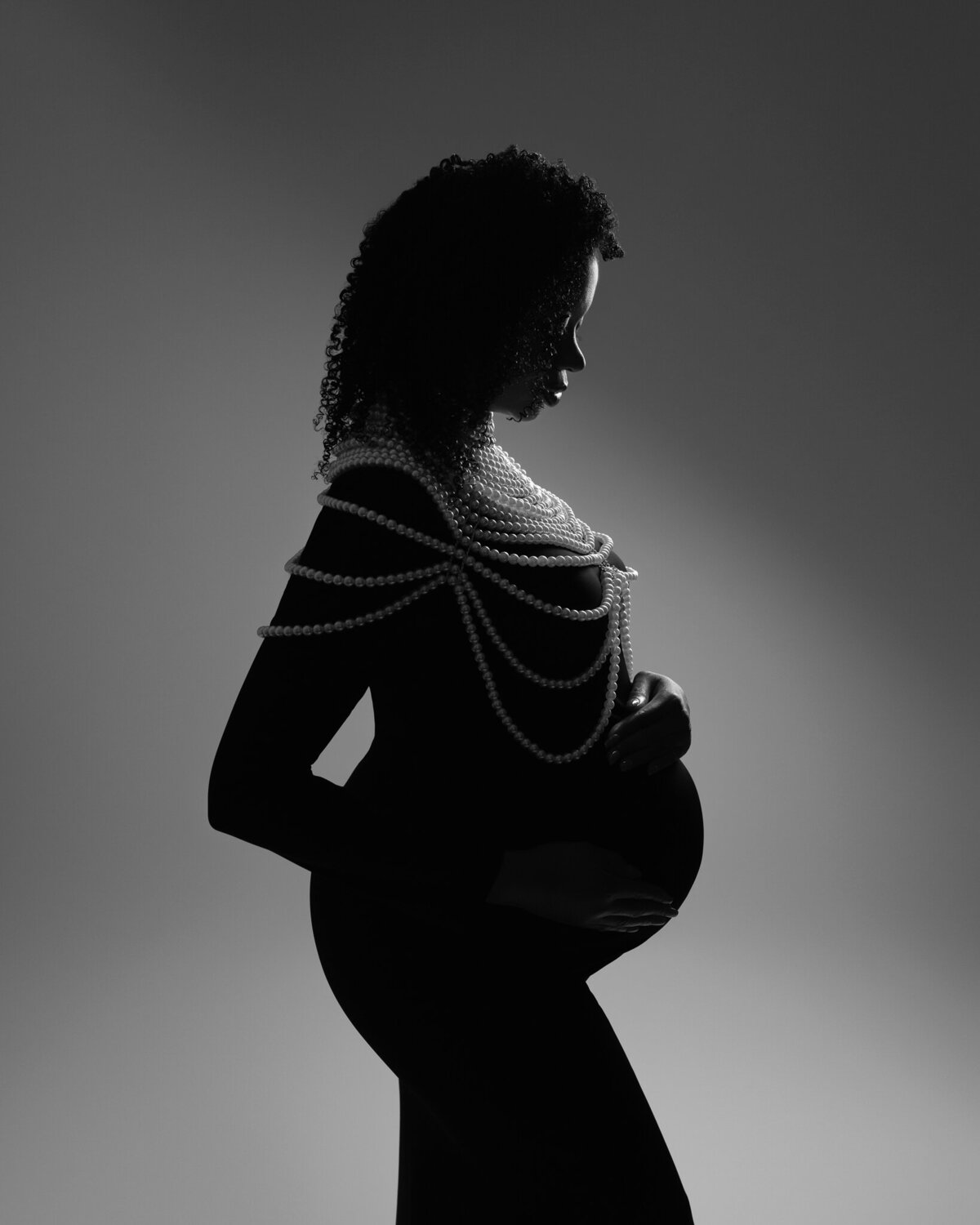 Black and white silhouette maternity portrait of a woman wearing a pearl body chain, photographed in Cedar Park, Texas.