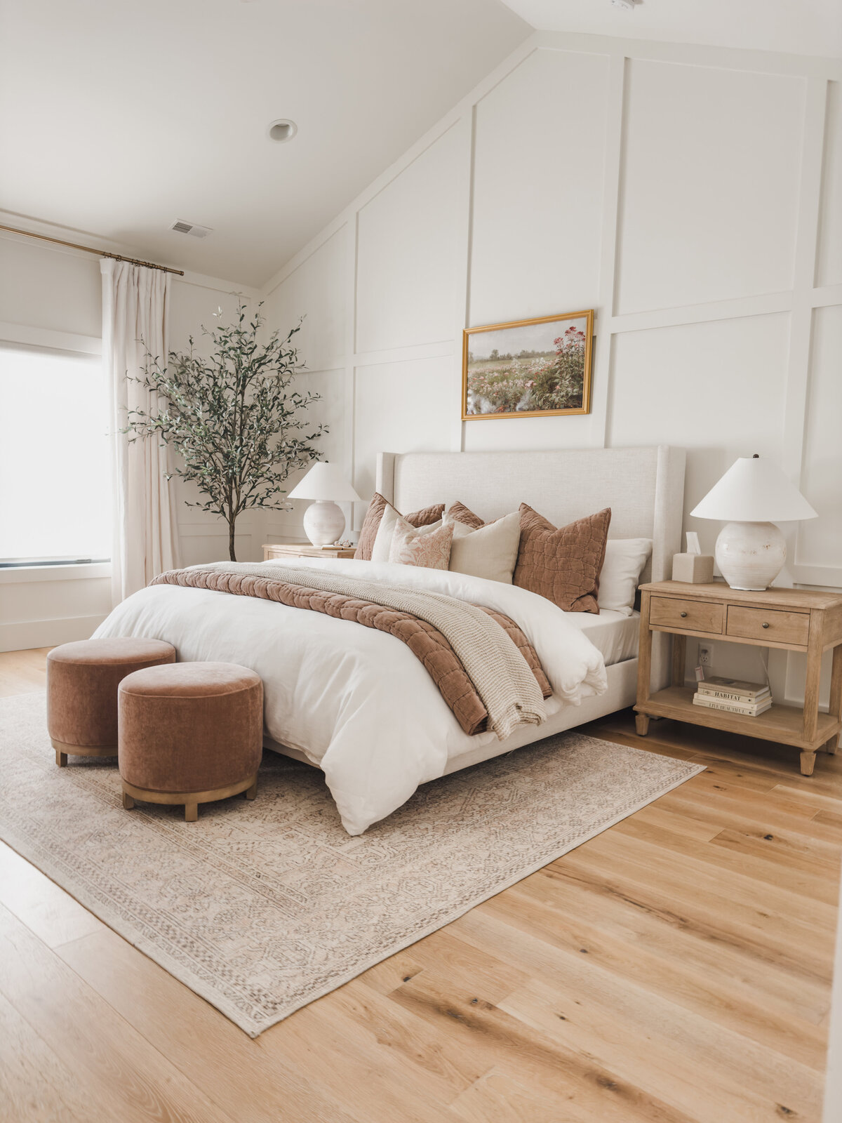 The primary bedroom at Woodlawn House features a vaulted ceiling and custom millwork in an elegant white