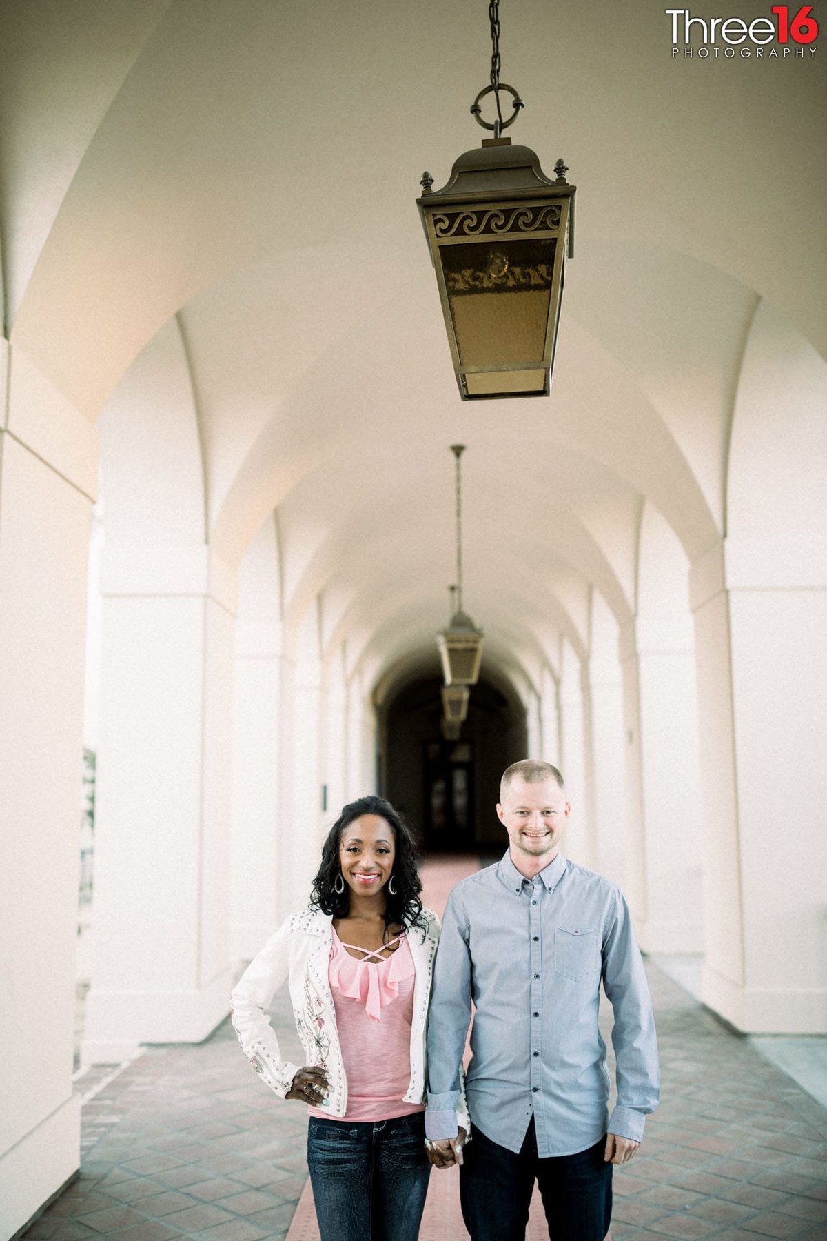 Engaged couple pose for photos in the Pasadena City Hall outdoor corridor