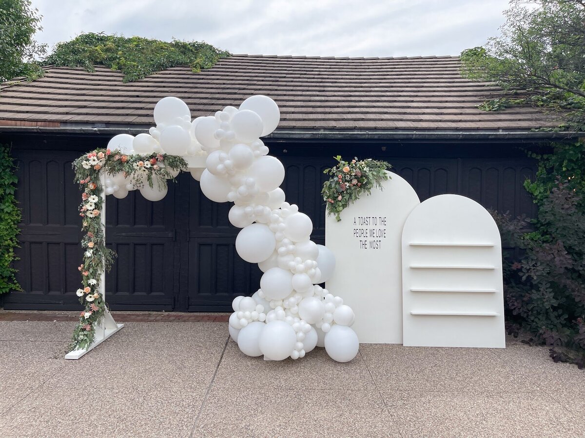 White balloons attached to a wededing ceremony arch