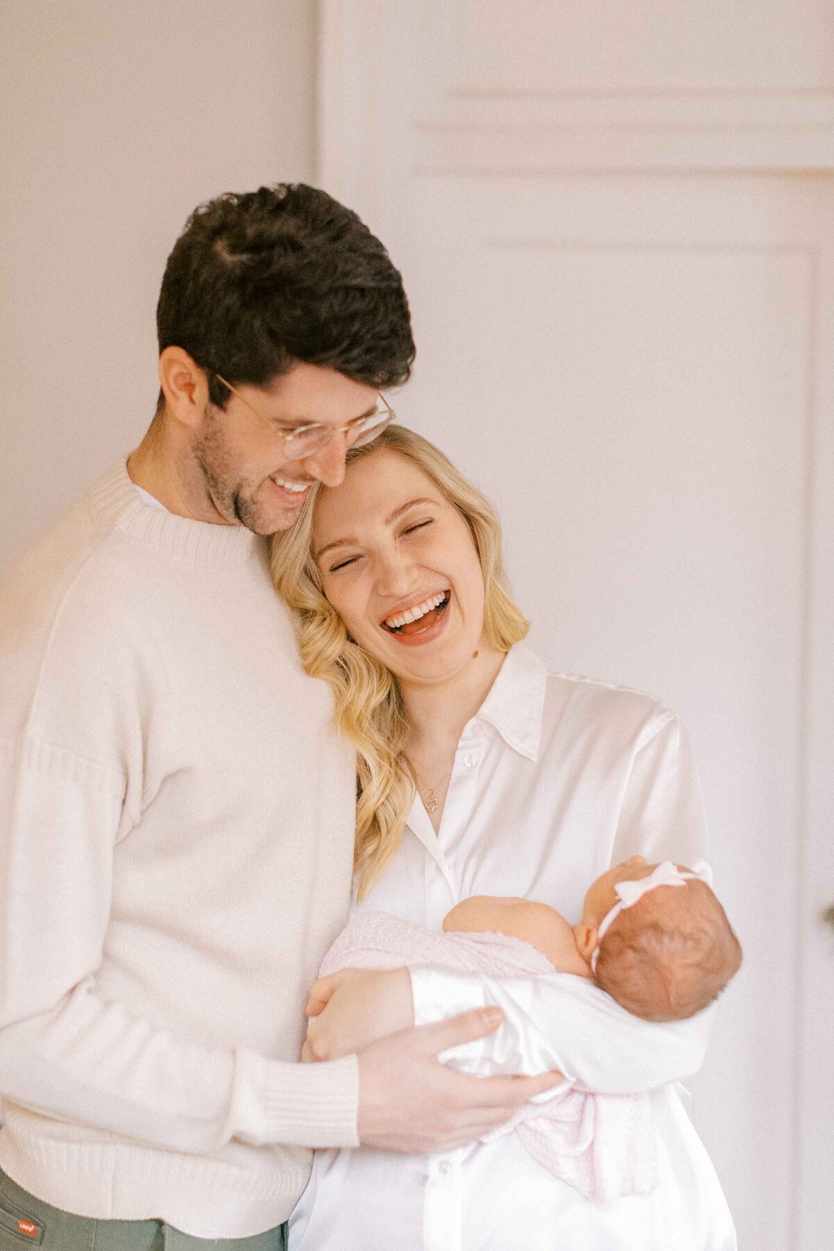 new mom and dad snuggling their baby girl and laughing