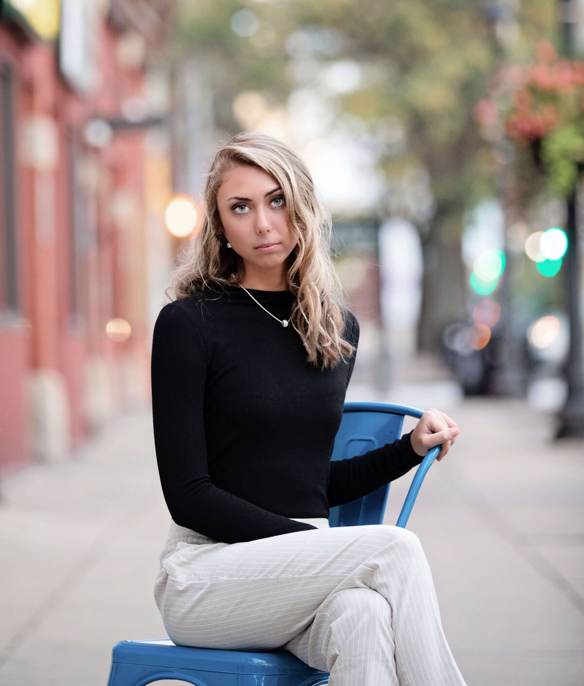 Erie Pa senior girl sitting on a blue chair on the sidewalk in downtown