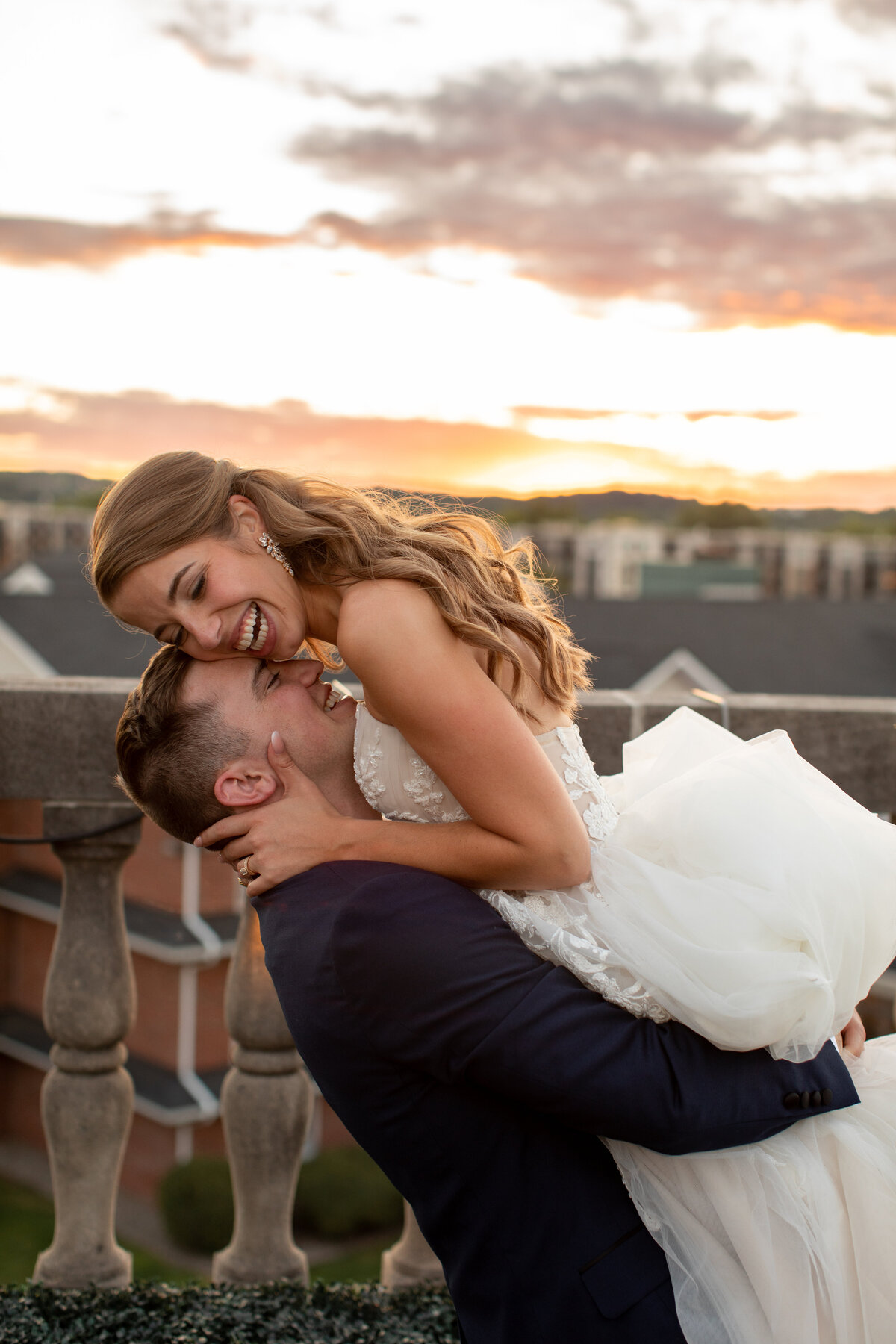Groom holding bride while they rest their faces against each other