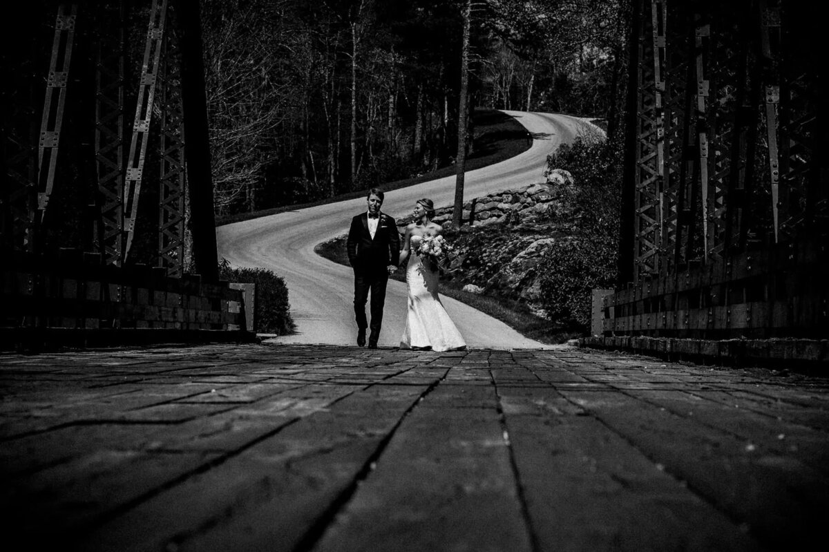 A wedding couple walking along an empty road.