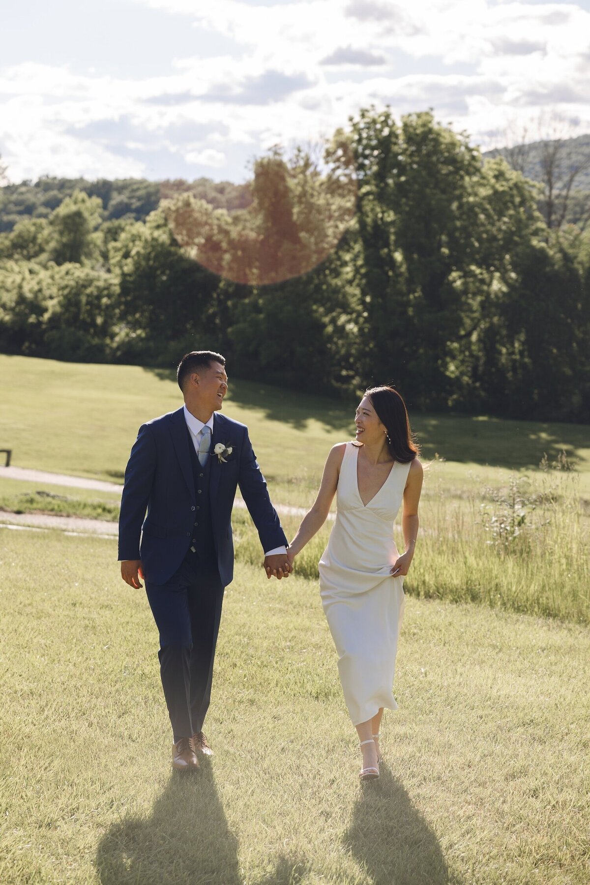 Bride and groom strolling hand-in-hand across golf course at sunset