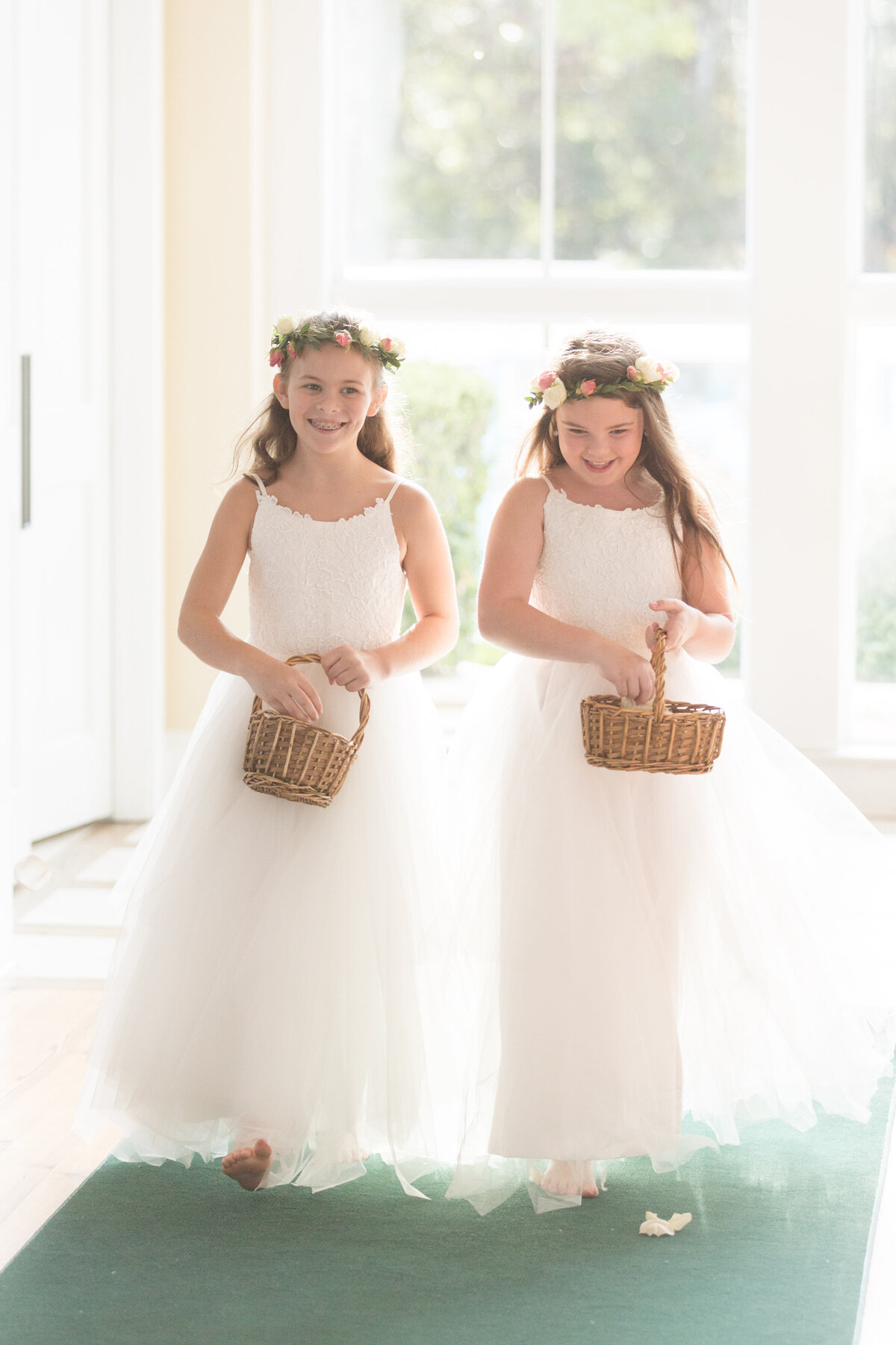 Two flower girls walk the isle as the wedding ceremony begins at St. Francis at The Point in Point Clear, Alabama.