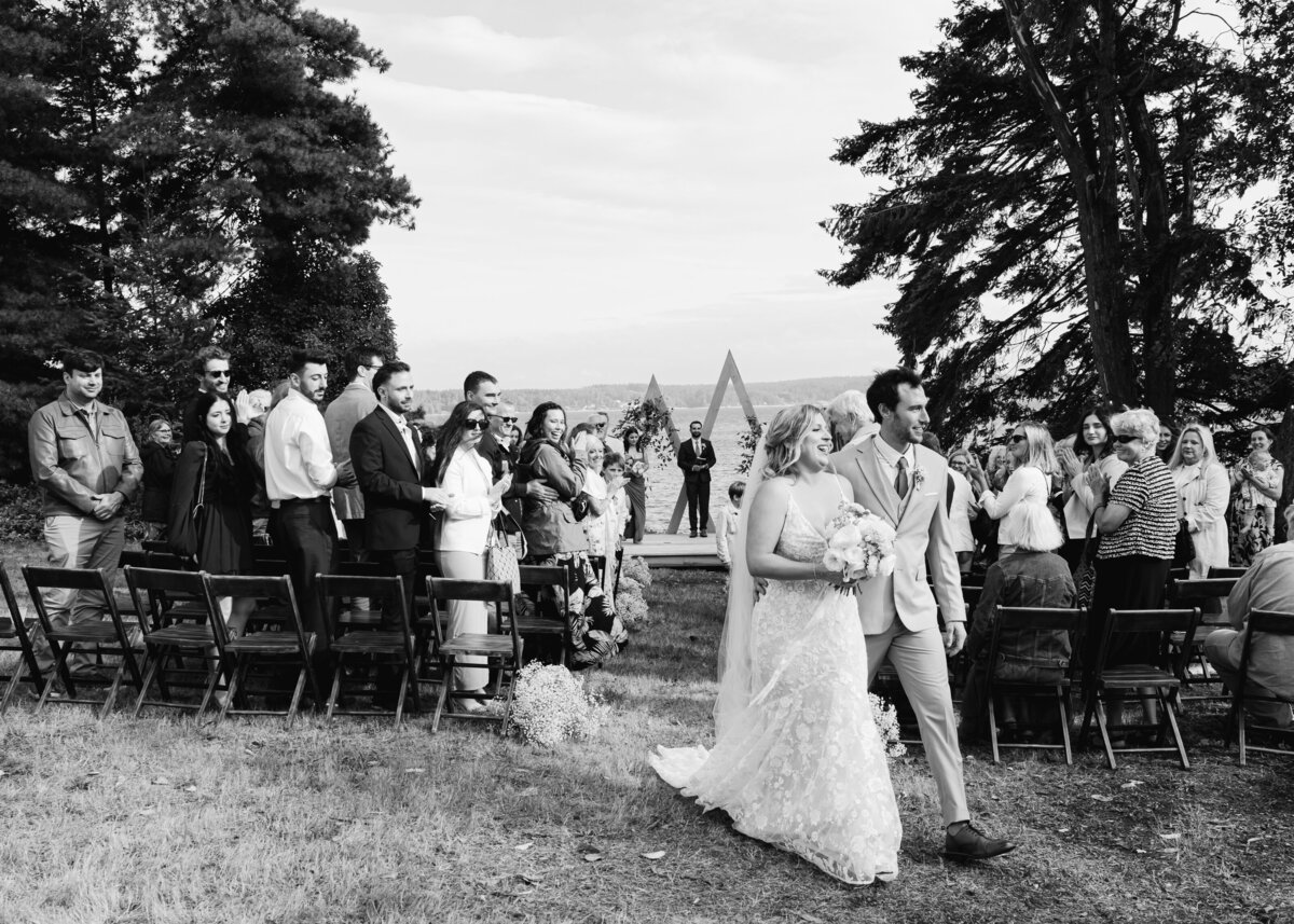 bride and groom walk down aisle in black and white