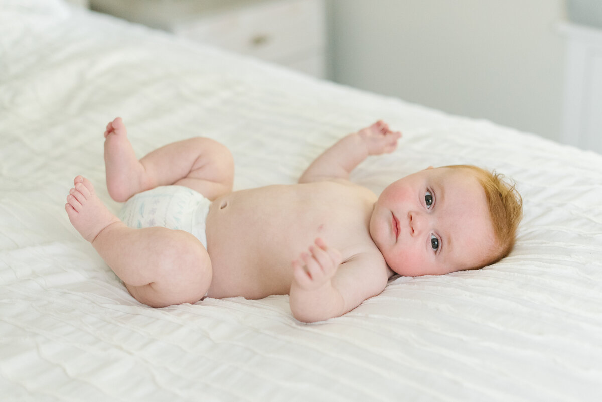 Baby laying down on white bed in white room