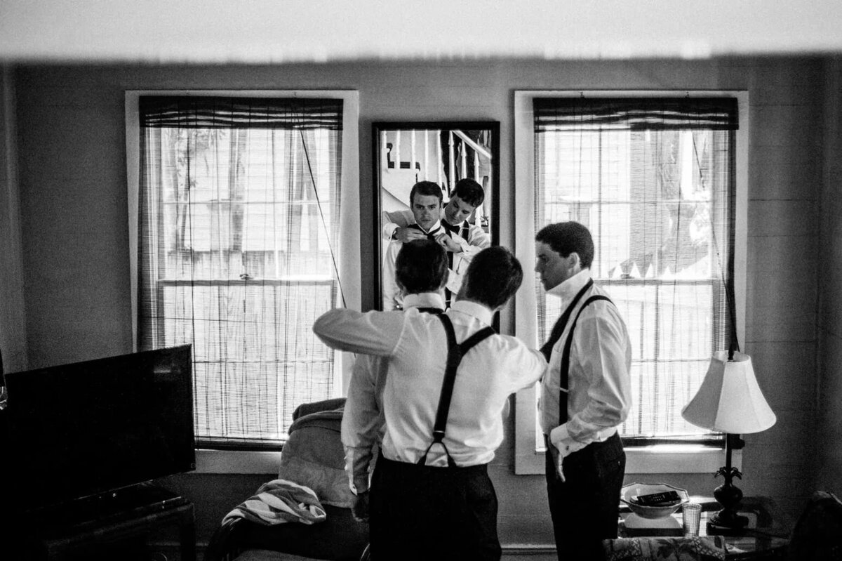 A group of men in suspenders and trousers prepare for a wedding