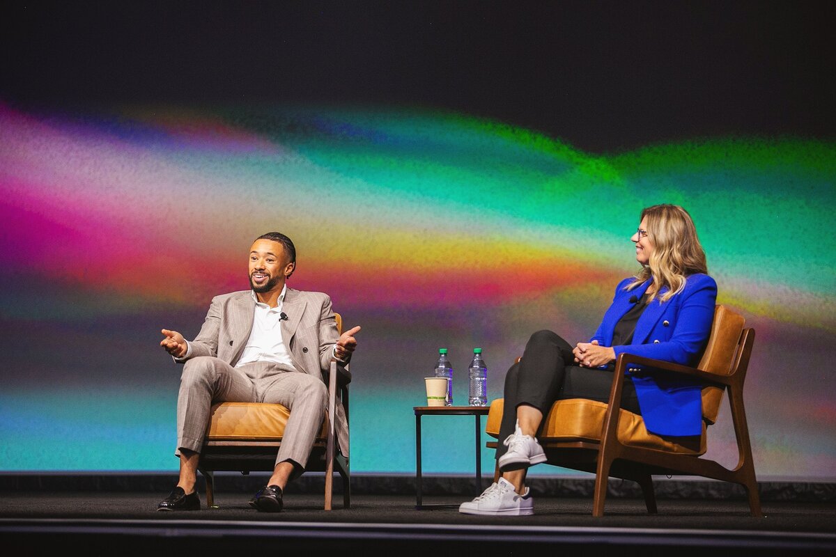 a-panel-discussion-with-business-leaders-on-stage-at-the-conference-in-indianapolis-with-a-vibrant-background