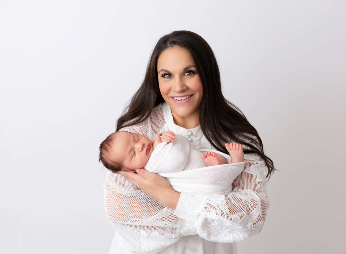 Modern baby photoshoot done in Brooklyn NY Mom holding her baby boy swaddled in white