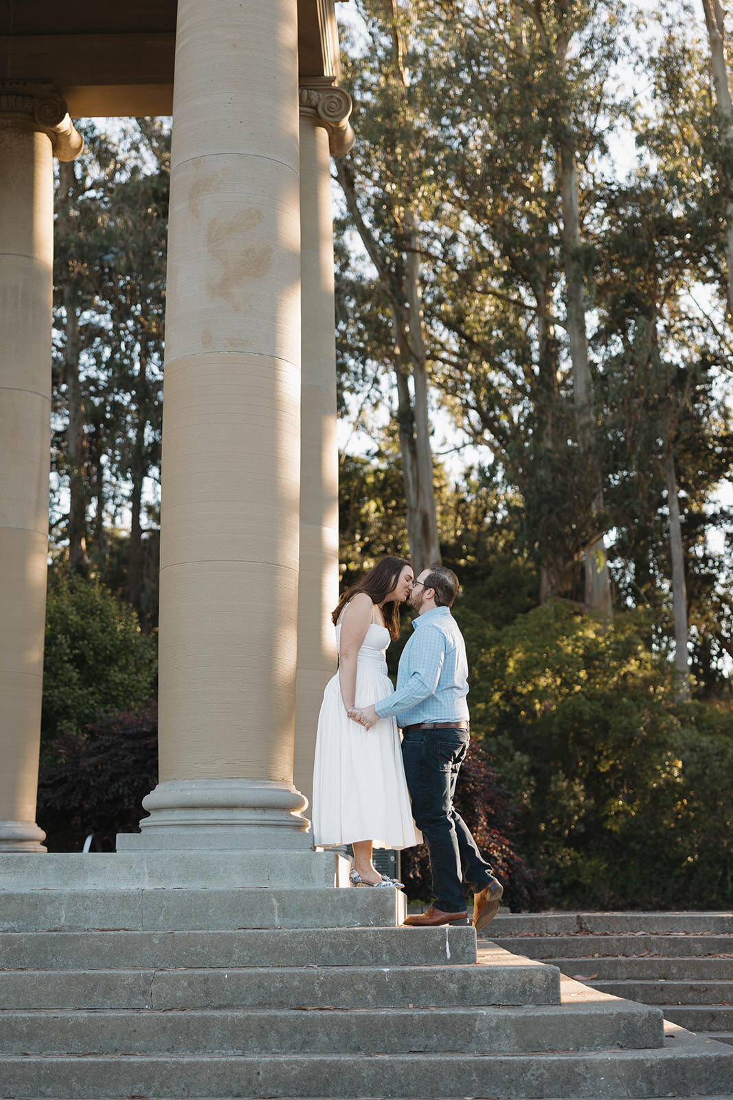 Engaged couple standing between tall stone columns