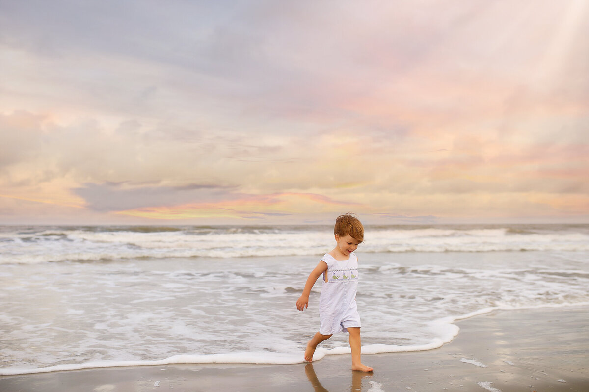 Little boy plays in the ocean during his Milestone Baby Photoshoot in Charleston, SC.