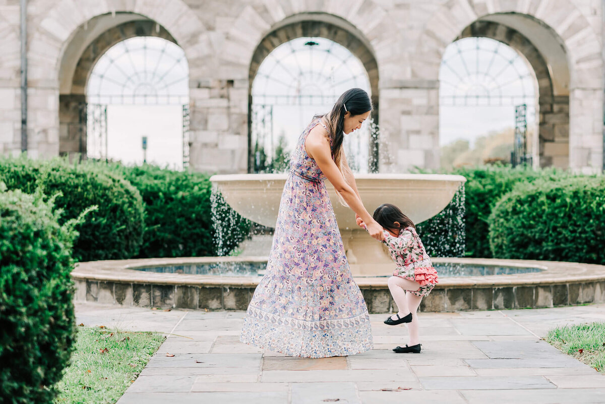 a woman dancing with her little girl in front of a fountain at St Anthony's Shrine
