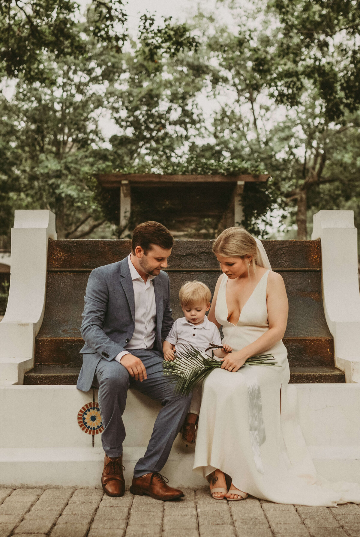 newlyweds & their son relax on fountain following intimate elopement ceremony
