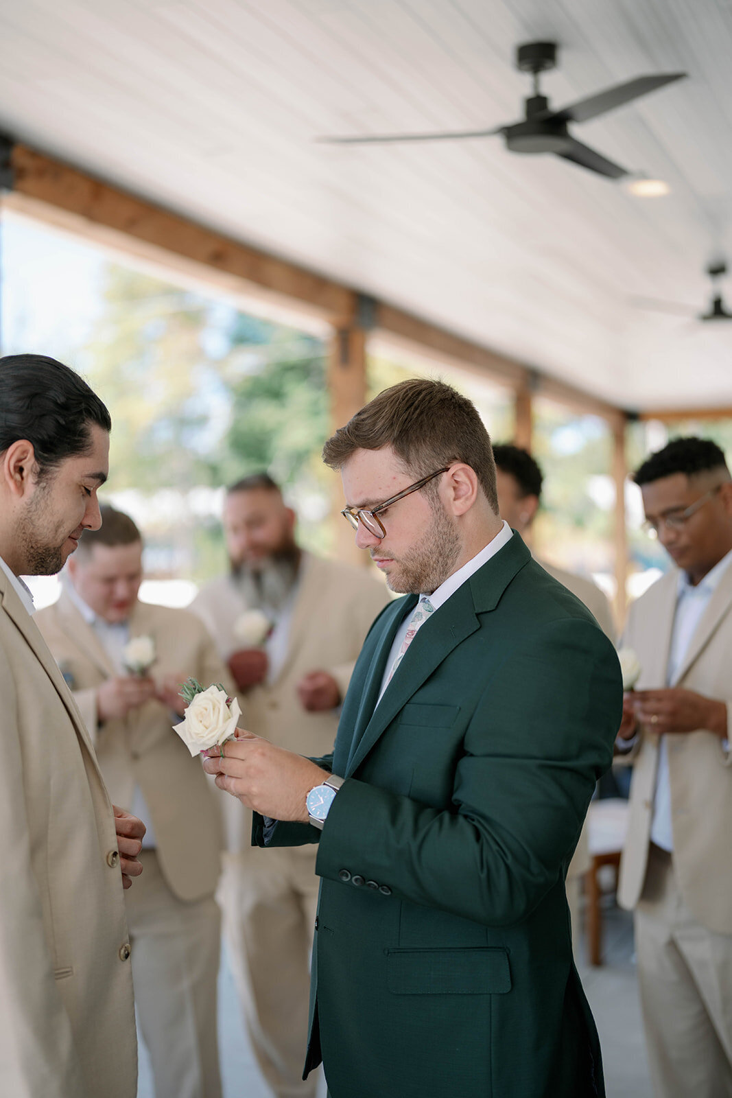 Groom pinning boutonnieres onto his groomsmen before the ceremony at The Ivy House.