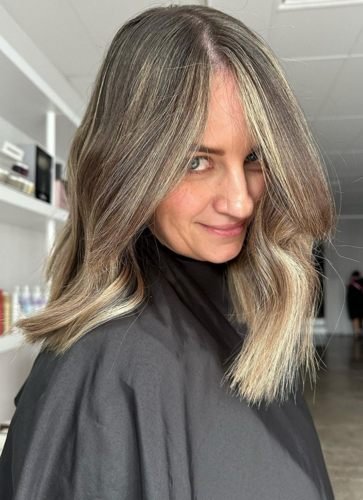 Woman I black hairdresser cape with freshly coloured hair - brunette with blonde pieces