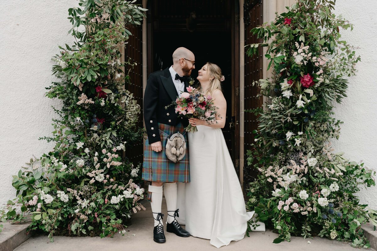 A bride and groom kiss outside Blair Castle in Perthshire after their wedding ceremony. They pose candidly for their wedding photographer.