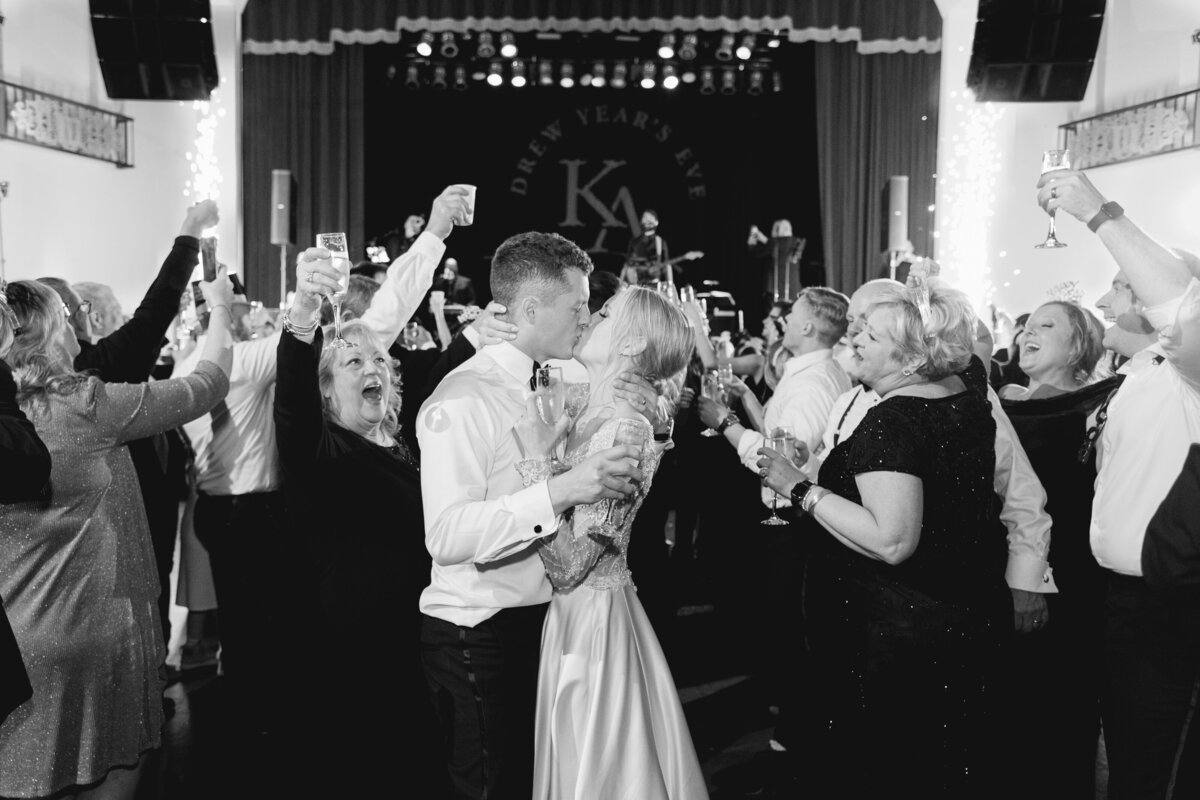 black and white image of wedding couple kissing at midnight during New Year's Eve reception