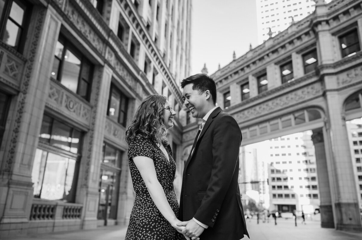 A couple laughs together while holding hands in the Wrigley Building courtyard in Chicago, Illinois