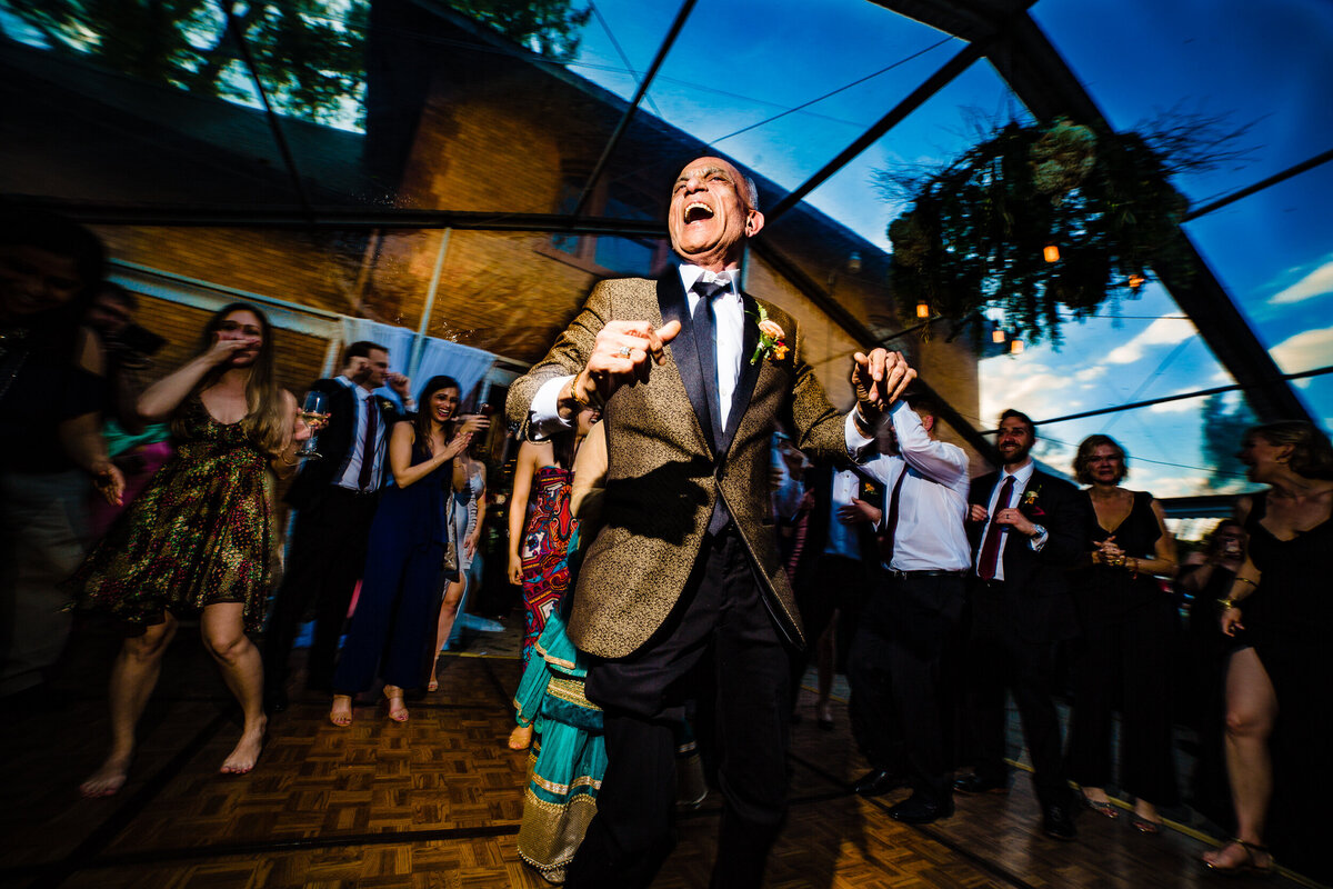 One of the top wedding photos of 2020. Taken by Adore Wedding Photography- Toledo, Ohio Wedding Photographers. This photo is of the father of the bride jumping during the wedding reception of an indian wedding at the FOrd Mansion in Toledo Ohio