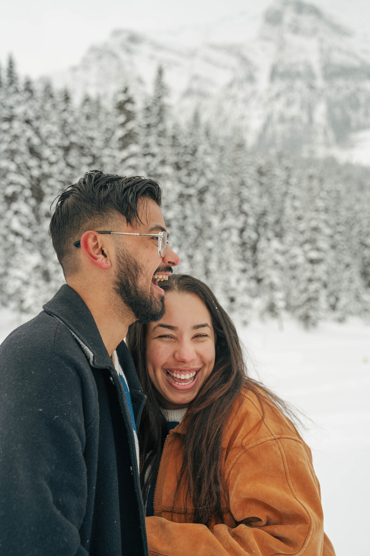 Candid moment of couple laughing during their snowy Banff photo session.