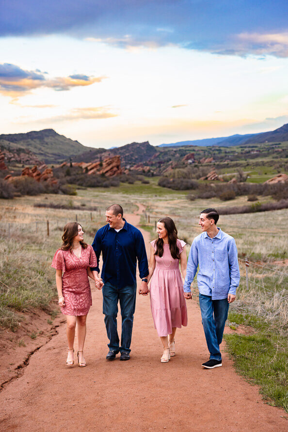 A family with two teens hold hands and walks at a park in Colorado.