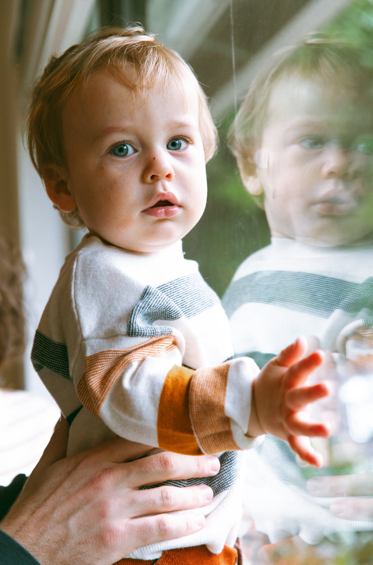 Toddler standing at the front of house window