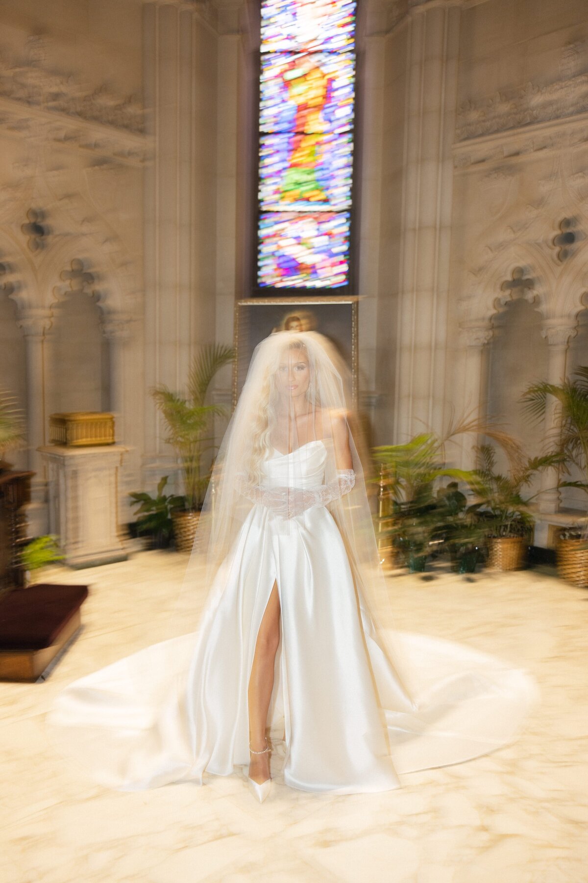 Bride walking down the aisle at Cathedral Basilica of the Sacred Heart in Newark NJ with stained glass windows behind her