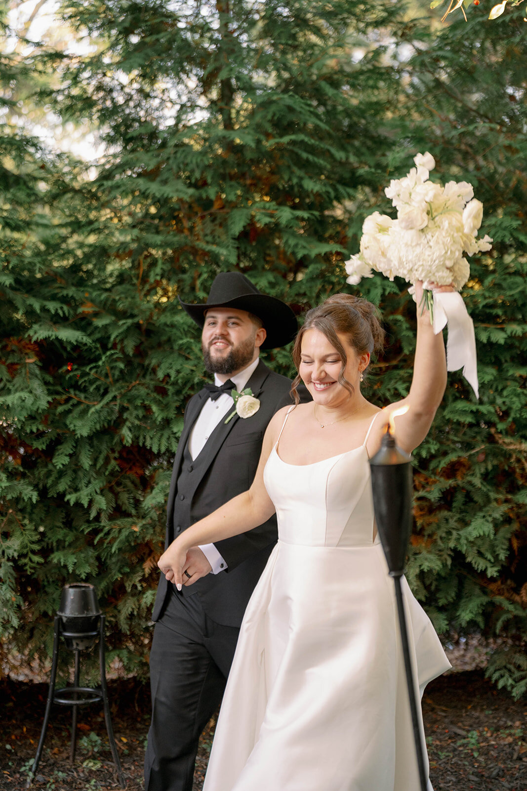 Bride joyfully lifting her bouquet while walking with the groom during Café Cortina wedding portraits.