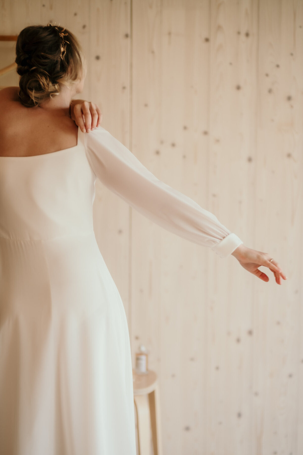 Nachdem die Braut ihr Kleid angezogen hat, richtet sie an der Schulter ihren langen Ärmel.