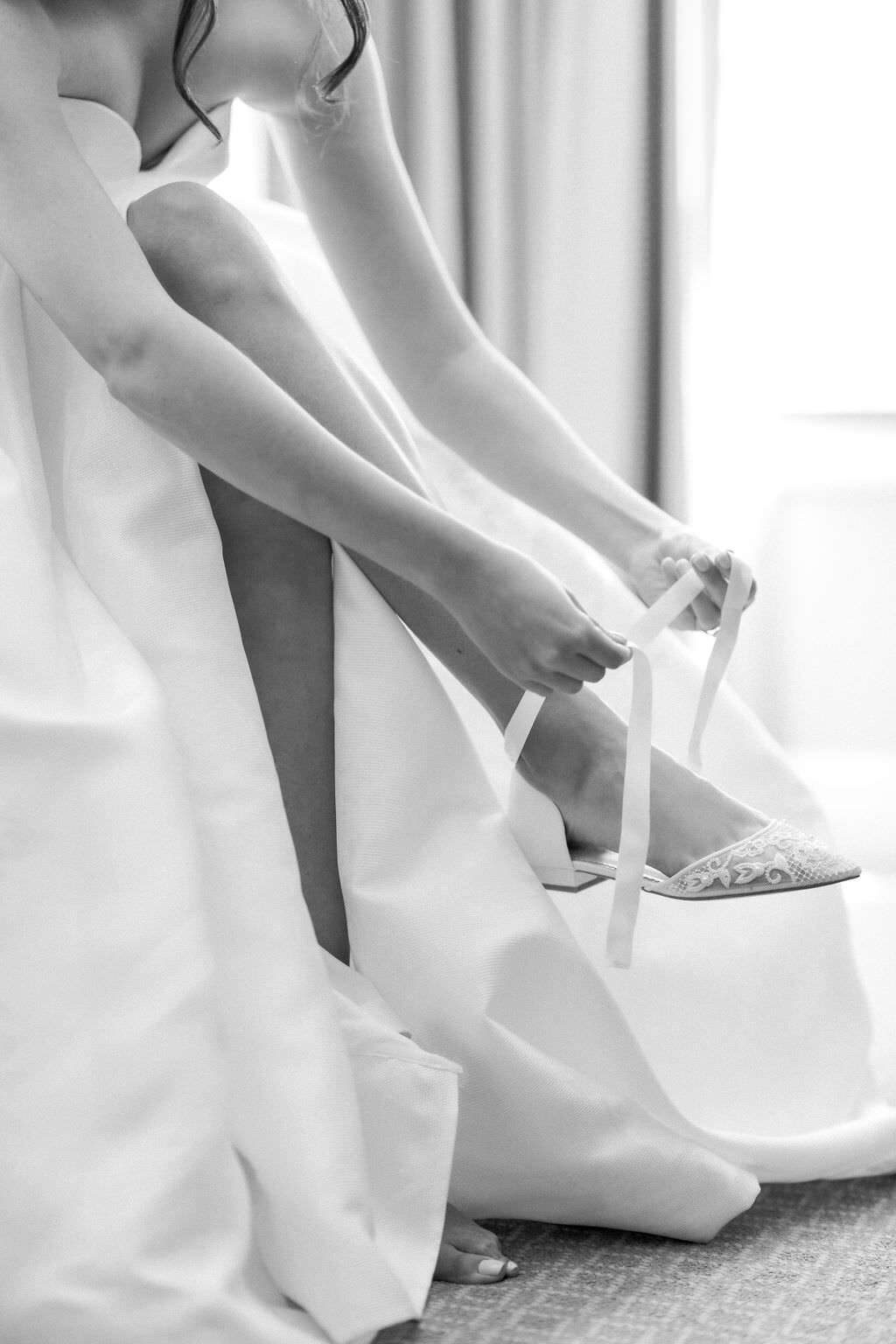 Close up of bride tying her wedding shoes