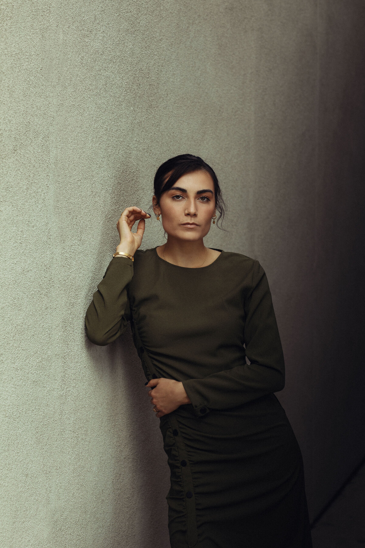 Portrait Photo Of Young Woman In Dark Green Dress Leaning Against a Wall Los Angeles