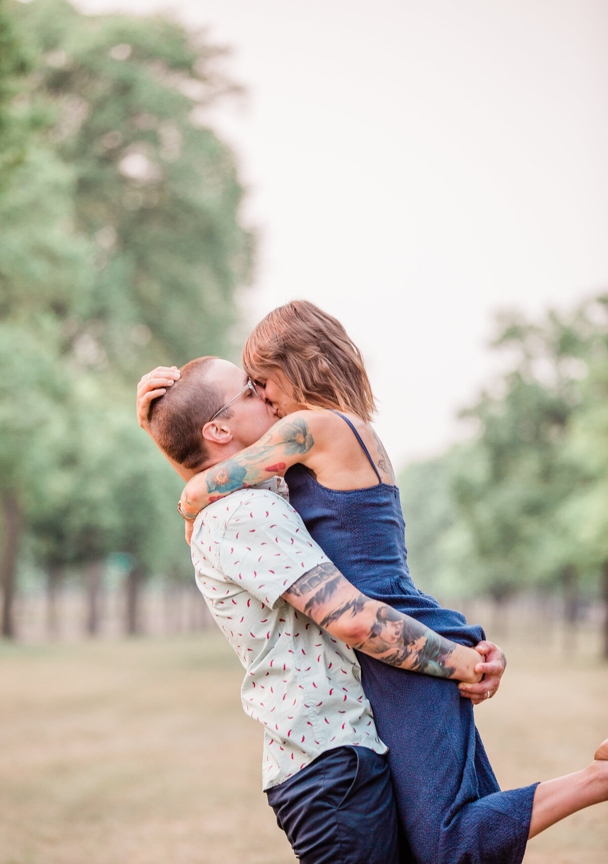 A woman in a blue dress is lifted and kissed by her partner in a mountain meadow for their Breckenridge Couples Photographer