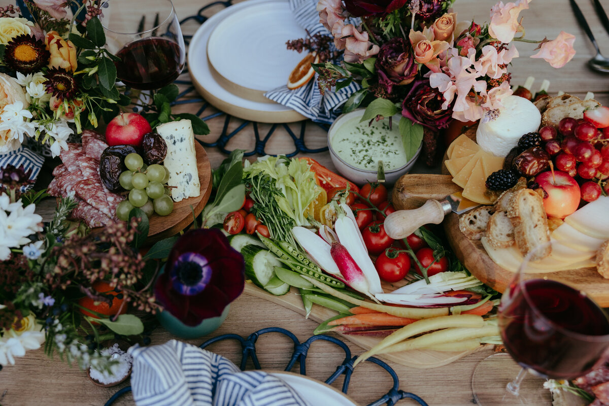 colorful crudites and dips on a high-end farm table at a chic alfresco dinner party.